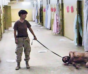 One of the many iconic photographs of the Abu Ghraib prison torture scandal: Lynndie England forcing an inmate, known to the guards as "Gus", to crawl and bark like a dog on a leash. England is holding a leash attached to a prisoner collapsed on the floor, U.S. Army / Criminal Investigation Command (CID). Seized by the U.S. Government.